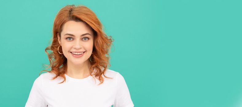 happy redhead woman with curly hair on blue background. Woman isolated face portrait, banner with copy space