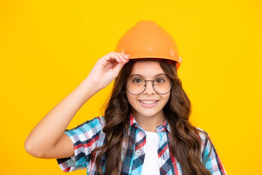 Close up portrait of teenager child builder in helmet. Teenage girl on repairing work isolated on yellow background