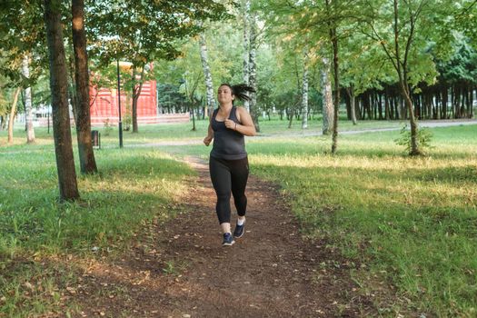 A charming brunette woman plus-size body positive practices sports in nature.