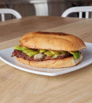 picture of delicious sandwich or Torta with meat, avocado and cheese on wooden table.. typical mexican food.