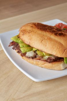 picture of delicious sandwich or Torta with meat, avocado and cheese on wooden table.. typical mexican food.