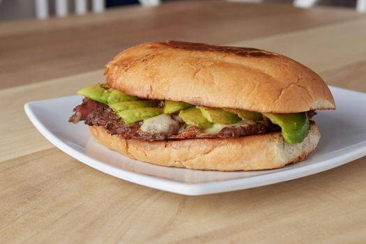 picture of delicious sandwich or Torta with meat, avocado and cheese on wooden table.. typical mexican food.