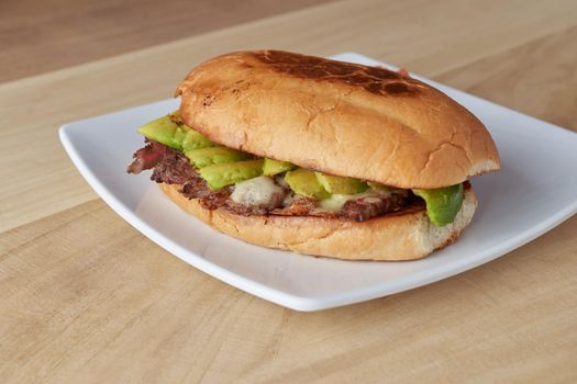 picture of delicious sandwich or Torta with meat, avocado and cheese on wooden table.. typical mexican food.