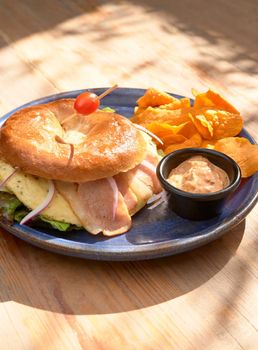 picture of delicious bagel with ham and cheese served with chipotle dressing and dehydrated bananas. bagel.