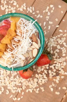 bowl of oatmeal with strawberry and granola on a wooden table. healthy breakfast.