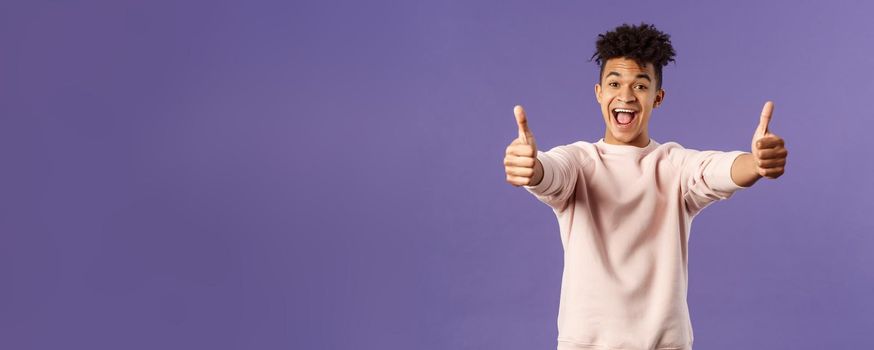 Portrait of satisfied young happy man think event was super cool, recommend use company service, assure in best quality, like and approve awesome product, standing purple background.