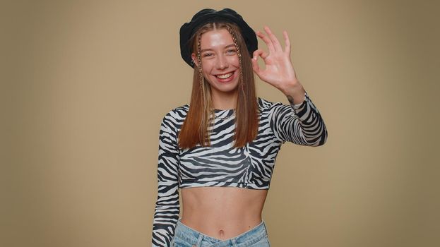 Ok. Lovely pretty young woman looking approvingly at camera showing ok gesture, like sign positive, approve something good. Adult stylish female girl isolated alone on beige studio background indoors
