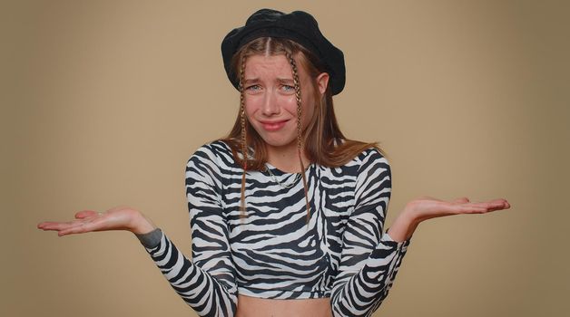 Pretty young woman raising hands in indignant expression, asking why, what reason of failure, demonstrating disbelief irritation by troubles. Adult stylish girl isolated on beige studio background