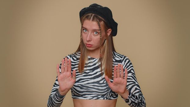Hey you, be careful. Young woman warning with admonishing finger gesture, saying no, be careful, scolding and giving advice to avoid danger, disapproval sign. Adult stylish girl on beige background