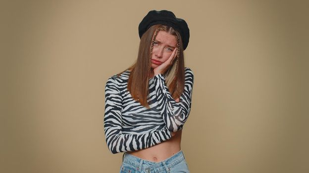 Lovely pretty young woman feeling hopelessness and loneliness, nervous breakdown, loses becoming surprised by lottery results, bad fortune, loss, unlucky news. Adult girl on beige studio background