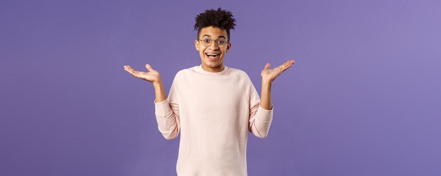 So what, I wear glasses. Portrait of unbothered, happy optimistic guy with dreads, wear round eyewear, shrugging carefree and raise hands sideways, smiling cheerful, have no worries.