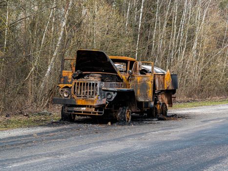 Road traffic accident of a car with fire. Car accident. Road in the forest. Damaged transport. Asphalt pavement. Traffic Laws. Military actions. Motor vehicle. Ukraine.