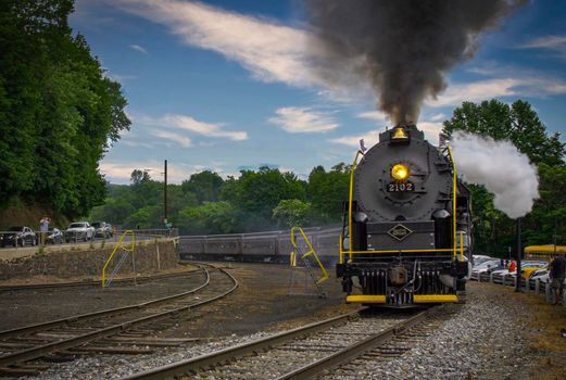 Jim Thorpe, Pennsylvania, July 02, 2022 - A View of a Restored Steam Passenger Train Blowing Smoke and Steam Traveling Pulling Traveling Around a Curve on a Sunny Day