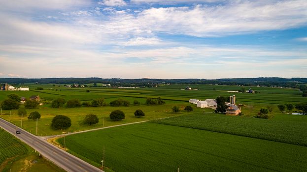 Aerial View of Farmlands With Barns and Silos, Looking Over the Hills and Fields of Rich Crops Growing on a Sunny Summer Day
