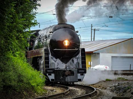 An Antique Restored Steam Engine Approaching Around a Curve Blowing Smoke, on a Sunny Day