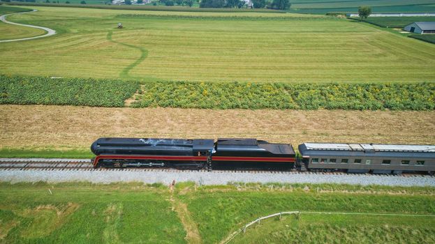 Drone Side View of an Antique Steam Engine, Approaching, Blowing Steam and Traveling Along the Countryside on a Sunny Day