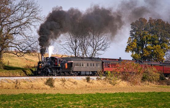 Ronks, Pennsylvania, November 8, 2021 - A View of a Steam Passenger Train on a Single Track Going Thru Rural Countryside on a Sunny Day