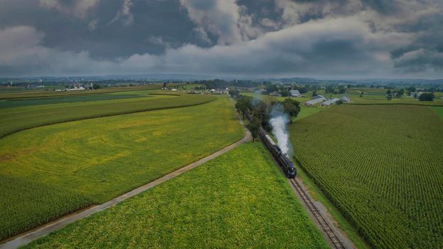 A Drone View of an Antique Steam Engine, Approaching, Blowing Steam and Traveling Along the Countryside on a Sunny Day