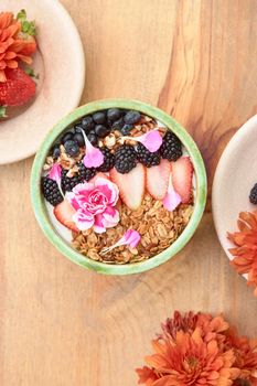 bowl of oatmeal with strawberry and granola on a wooden table. healthy breakfast.