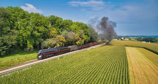 Drone View of an Antique Steam Engine, Approaching, Blowing Steam and Traveling Along the Countryside on a Sunny Day