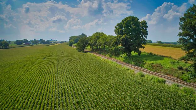 Drone View of Amish Countryside With Barns and Silos and a Single Railroad Track Traveling Through It, on Sunny Day.