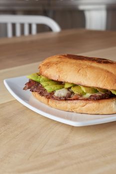 picture of delicious sandwich or Torta with meat, avocado and cheese on wooden table.. typical mexican food.