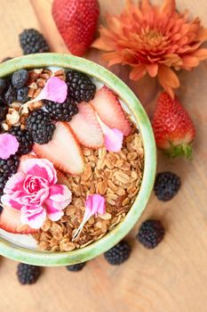 bowl of oatmeal with strawberry and granola on a wooden table. healthy breakfast.