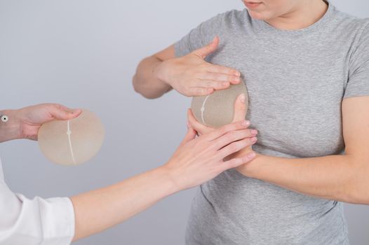Caucasian woman trying on breast implants. A plastic surgeon helps a patient with a choice