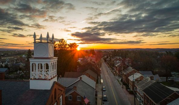 Aerial View of a Sunrise in a Small Town With Light Coming Over Horizon Seen near a Steeple on a Beautiful Spring Morning