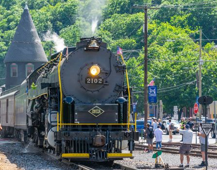 Ronks, Pennsylvania, November 8, 2021 - A View of a Restored Steam Freight Train Blowing Smoke and Steam Traveling Along a Rural Countryside on a Sunny Day