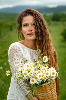 A middle-aged woman holds a large bouquet of daisies in her hands. Wildflowers for congratulations.