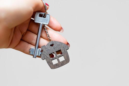 A woman's hand holds a house key on a white background with copy space. Real estate agent. Buying a house, apartment