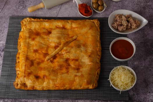 close-up of the filling of a tuna empanada with its ingredients on a wooden board with a brick background