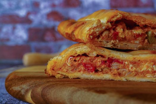 close-up of the filling of a tuna empanada with its ingredients on a wooden board with a brick background