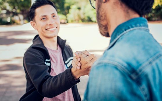 Two teenage friends shaking hands at each other outdoors. Two people shaking hands on the street. Concept of two friends greeting each other with handshake on the street