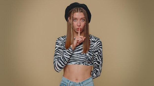 Shh be quiet please. Pretty young scared woman presses index finger to lips makes silence gesture sign do not tells secret. Adult stylish female girl isolated alone on beige studio background indoors
