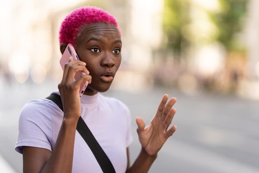 Portrait of a young African woman talking energetically on her mobile phone in the street.