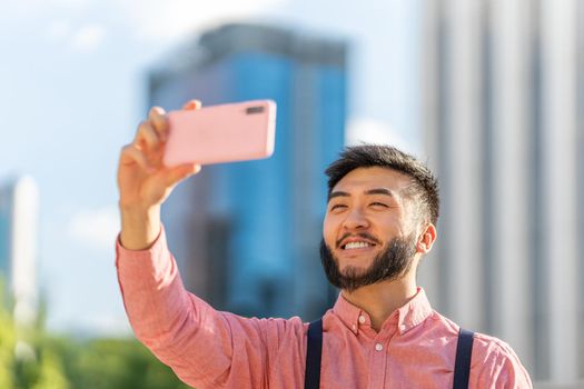 Photo with copy space of a stylish asian man taking a selfie with the mobile next to a trade center