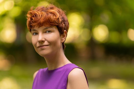 Portrait of a non-binary gender person smiling at the camera with a relaxed attitude in a park