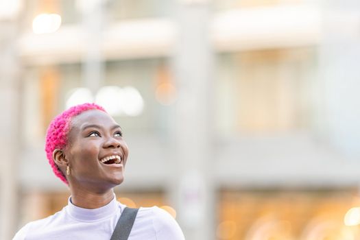 Portrait with copy space of a beauty smiling young african woman looking up to the sky outdoors