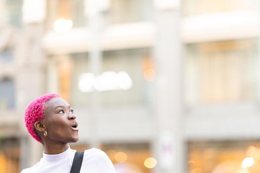 Young african woman looking up with surprised expression outdoors