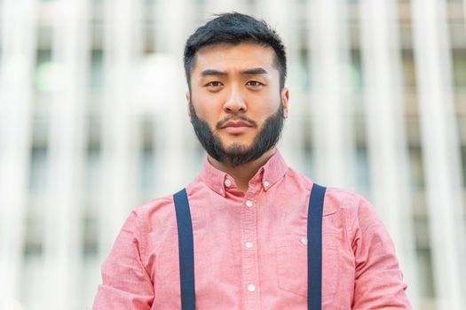 Low angle view portrait of an asian man in casual clothes looking to the camera outside a city