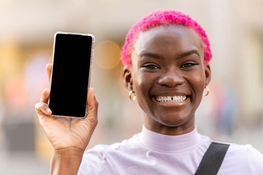 Afro woman with toothy smile showing the screen of a mobile. Mockup concept