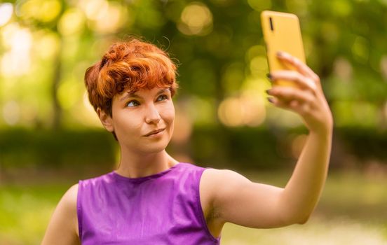 Portrait with selective focus on a non-binary gender person taking a selfie in the park