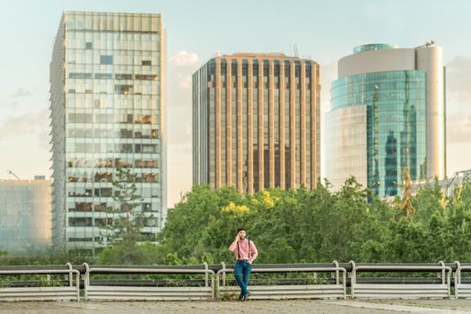 Asian man talking to his mobile phone from a viewpoint overlooking an urban landscape