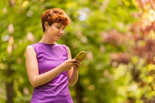 Portrait with copy space of a non-binary gender person using a mobile phone in the park