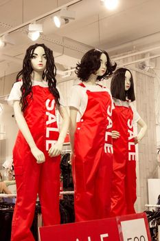 Female mannequins in woman red dungarees in fashion clothing store, black friday sale shopping concept, seasonal offer promo, vertical image