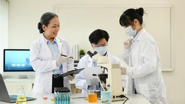 Senior female supervisor and young biotechnology specialist scientists conducting experiment in a laboratory.