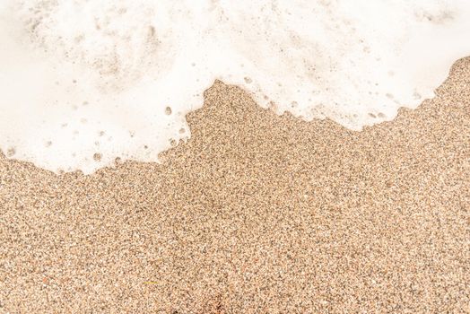 Top view full frame of textured background of brown sand with sea foam on beach