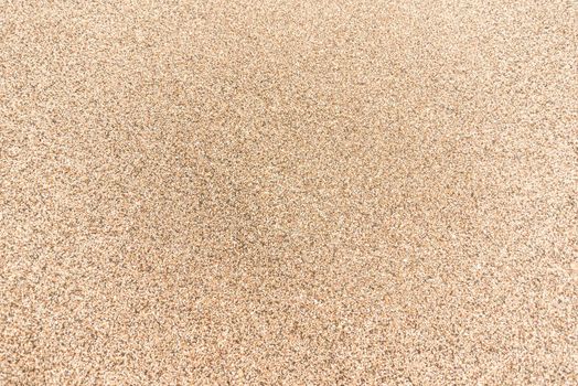 Full frame background of textured surface of sand with coarse grains of yellow color